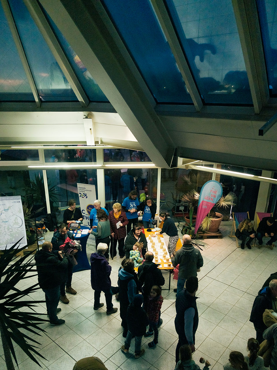 Das Bild zeigt ca. 20 Personen in einer gefließten Halle mit Glasfassade, sichtbaren Stahlträgern und Glasflächen im Dach.